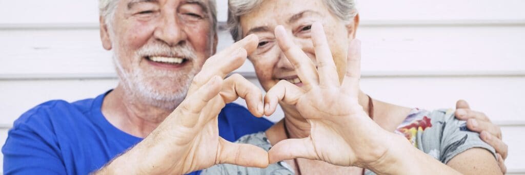 Senior people love hearth sigh with hands in banner header composition. Happy old couple